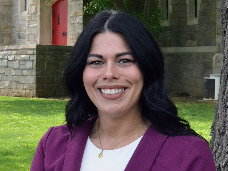 Graduate student Christine Compton smiles while standing outdoors on the campus of Muhlenberg College.
